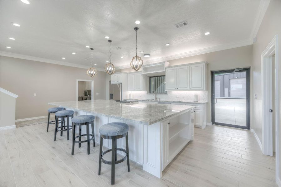 Kitchen with huge granite countertops with an island with cooktop and ample lighting (Building B) Kitchen with huge granite countertops with an island with cooktop and ample lighting (Building B)