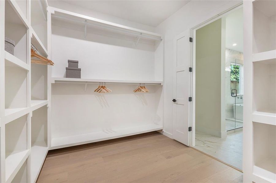 Walk in closet with light hardwood / wood-style floors