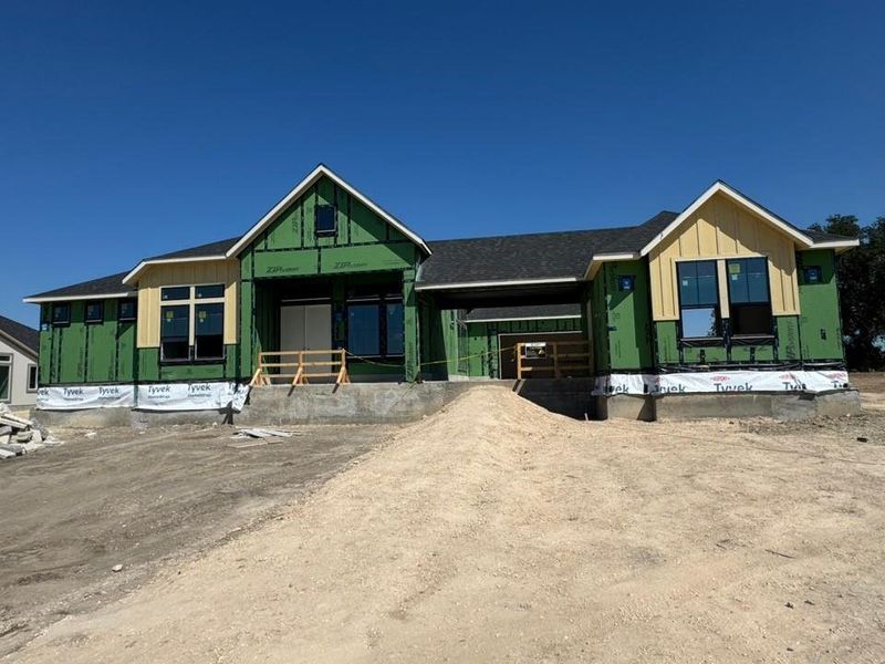 Unfinished property with board and batten siding, covered porch, and roof with shingles