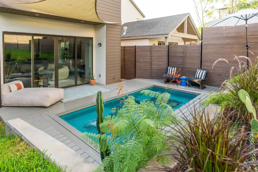 A private swimming pool is bordered by composite decking and modern architectural siding. A private swimming pool is bordered by composite decking and modern architectural siding.