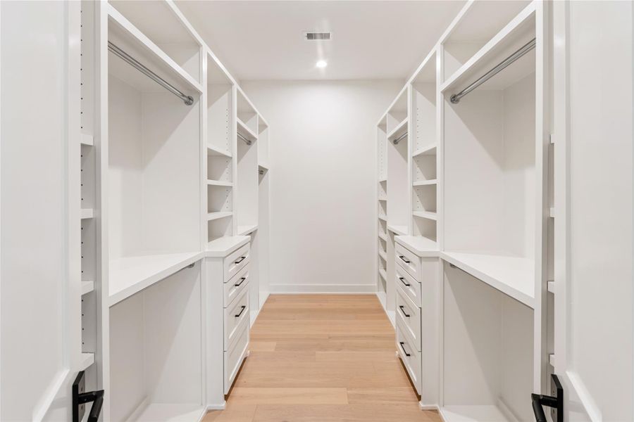 The primary bedroom features the luxury of two individual walk-in closets, each designed with extensive storage options for maximum functionality. This premium amenity transforms daily routines into spa-like experiences with dedicated space for each partner. This is the "less larger" of the two closets.