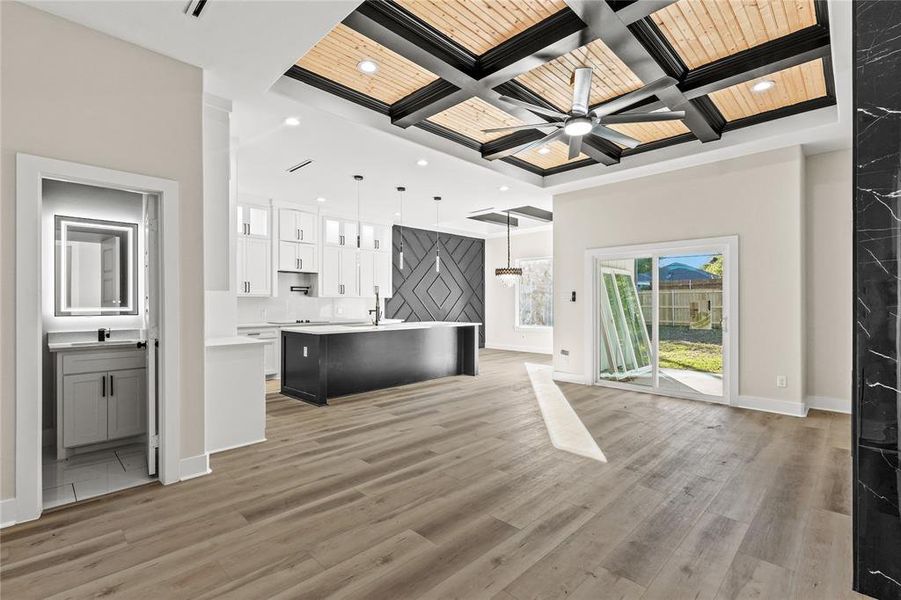 Kitchen featuring pendant lighting, light wood-type flooring, white cabinetry, and coffered ceiling