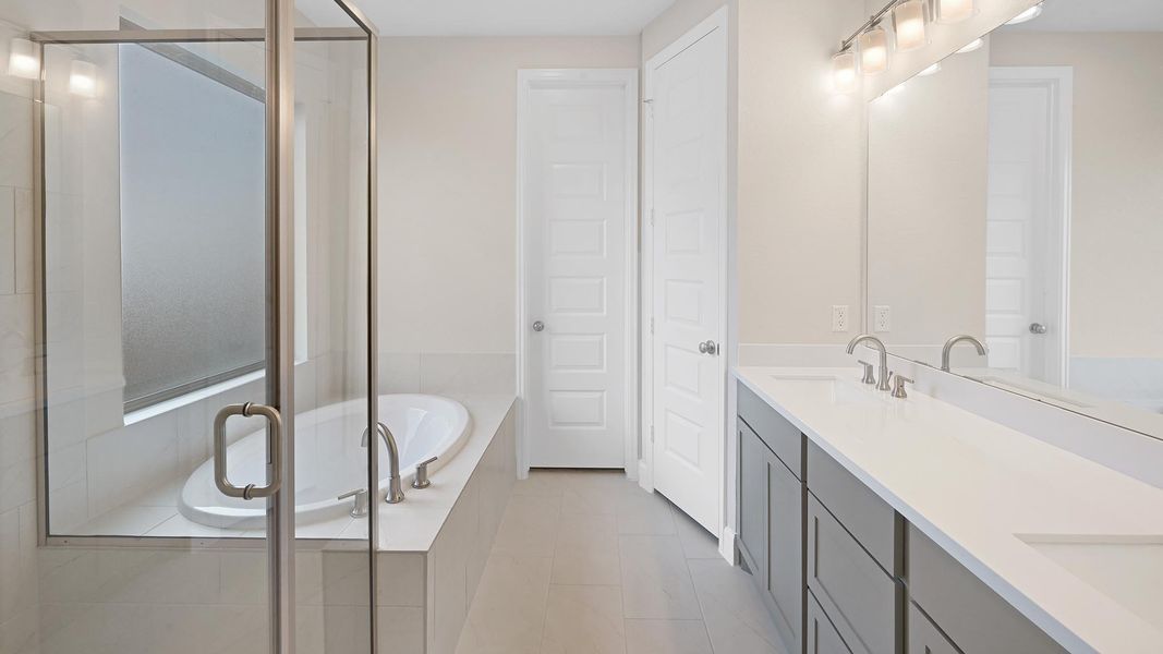 Full bathroom with double vanity, a shower stall, a garden tub, and light tile patterned flooring