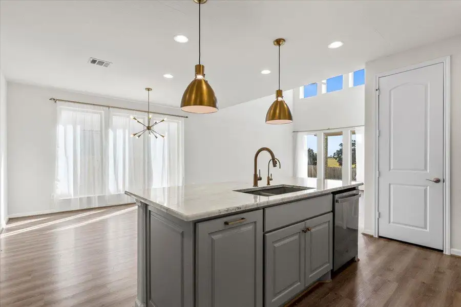 Kitchen with gray cabinetry, light stone counters, recessed lighting, a kitchen island with sink, and dark wood-style floors Kitchen with gray cabinetry, light stone counters, recessed lighting, a kitchen island with sink, and dark wood-style floors