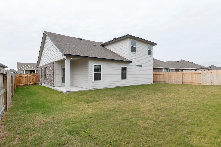Rear view of property featuring a fenced backyard, a patio area, roof with shingles, brick siding, and a gate