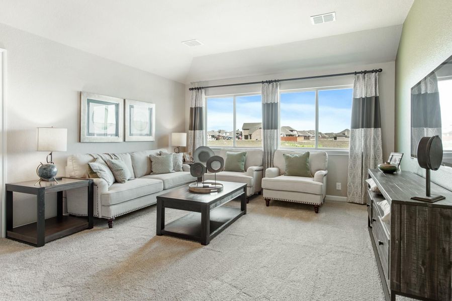 Living room with beige sofa, armchair, wood coffee table, carpet flooring, and large window with striped curtains Living room with beige sofa, armchair, wood coffee table, carpet flooring, and large window with striped curtains