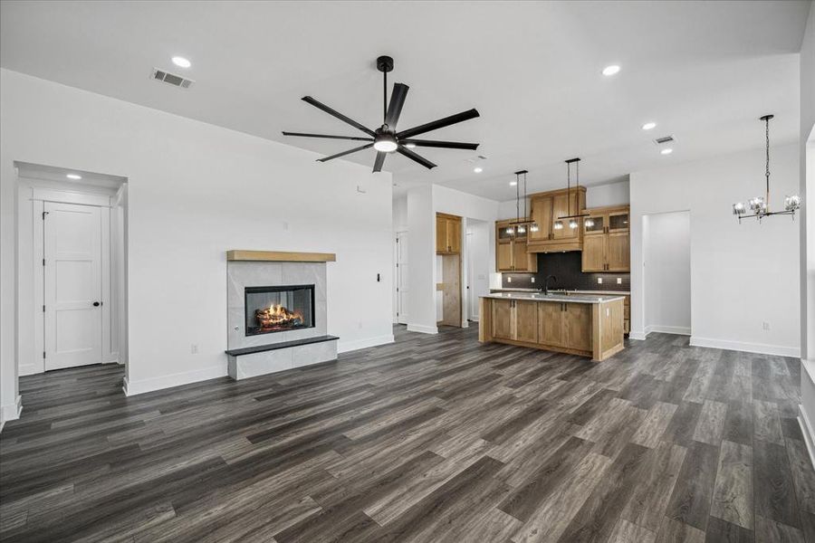 Unfurnished living room with ceiling fan, dark wood finished floors, a chandelier, recessed lighting, and a fireplace