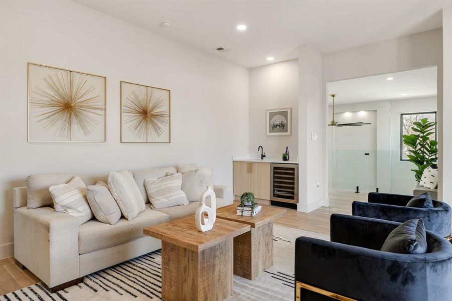 Living room with light hardwood / wood-style floors, wine cooler, and indoor wet bar