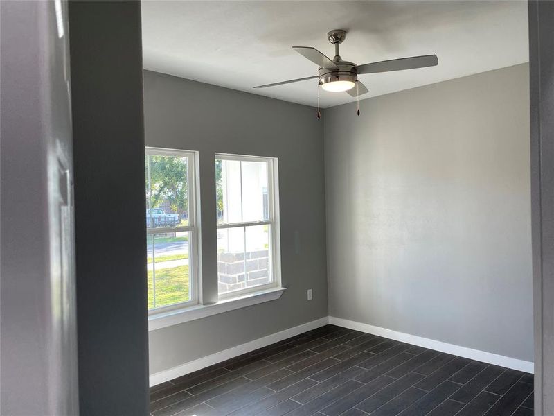 Unfurnished room with dark hardwood / wood-style flooring, ceiling fan, and a wealth of natural light