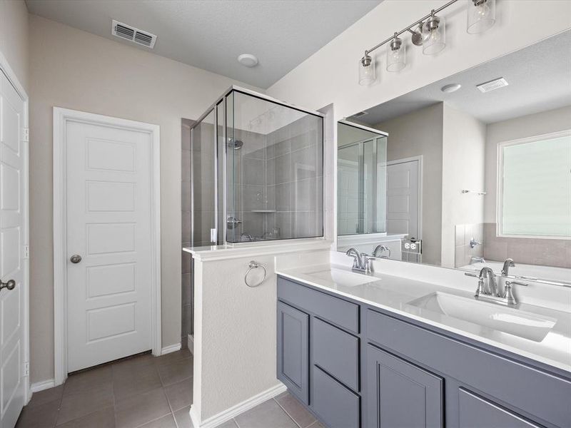 Full bathroom featuring a stall shower, light tile patterned floors, and double vanity Full bathroom featuring a stall shower, light tile patterned floors, and double vanity