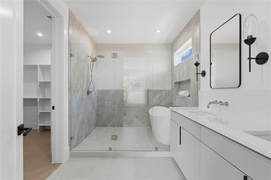 Contemporary bathroom featuring a frameless glass shower enclosure, a freestanding soaking tub, a dual vanity with integrated sinks, a built-in shower niche, and matte black wall sconces
