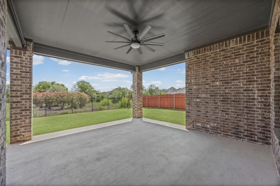 A spacious covered patio invites relaxation with a lush green backyard view.