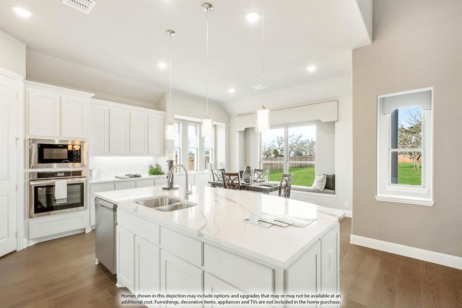 Kitchen with white cabinets, large island with quartz countertop, stainless steel appliances, and pendant lights over dining area.