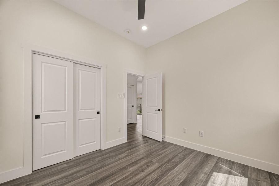 This room features modern wood flooring, neutral walls, and recessed lighting. It includes a closet with sliding doors and an open door leading to another space, creating a bright and versatile area. This room features modern wood flooring, neutral walls, and recessed lighting. It includes a closet with sliding doors and an open door leading to another space, creating a bright and versatile area.