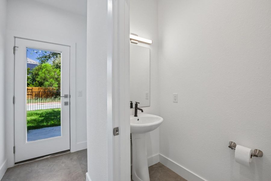 A glass door opens to the rear yard beside a modern guest half bath.