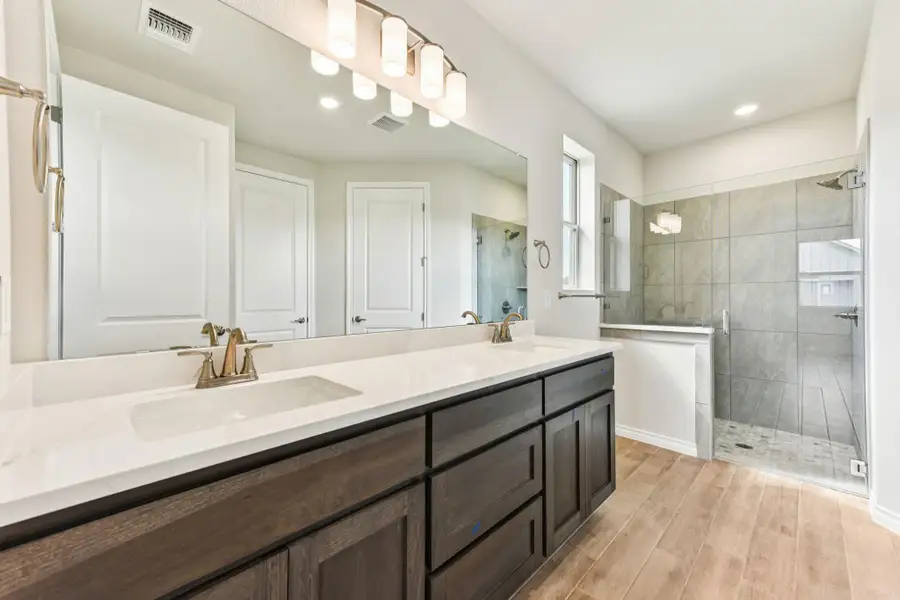 Full bathroom with double vanity, a shower stall, wood tiled floors, and recessed lighting