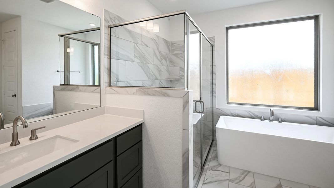 Bathroom featuring light marble finish floors, a soaking tub, a stall shower, and vanity Bathroom featuring light marble finish floors, a soaking tub, a stall shower, and vanity