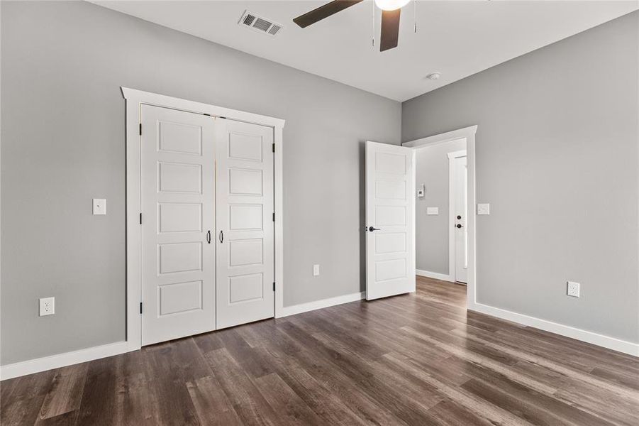 Unfurnished bedroom with dark wood-style floors, a closet, and a ceiling fan