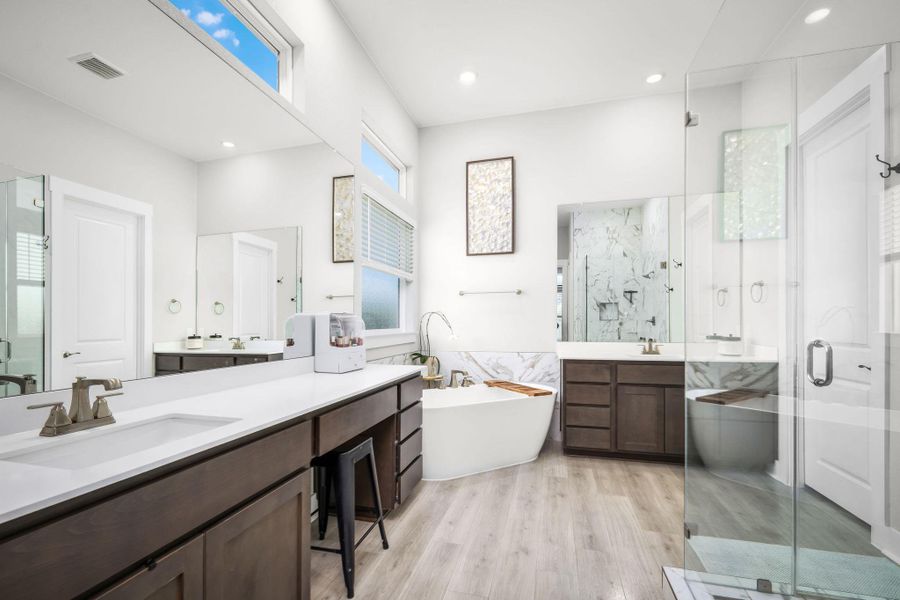 A pristine primary bathroom offers a dual vanity, deep soaking tub, and a spacious walk-in shower.