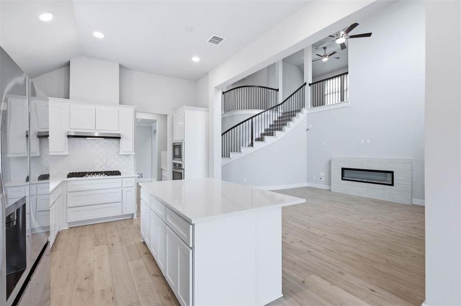 Kitchen and breakfast area featuring a large island, white cabinetry, and open sightlines throughout the home.