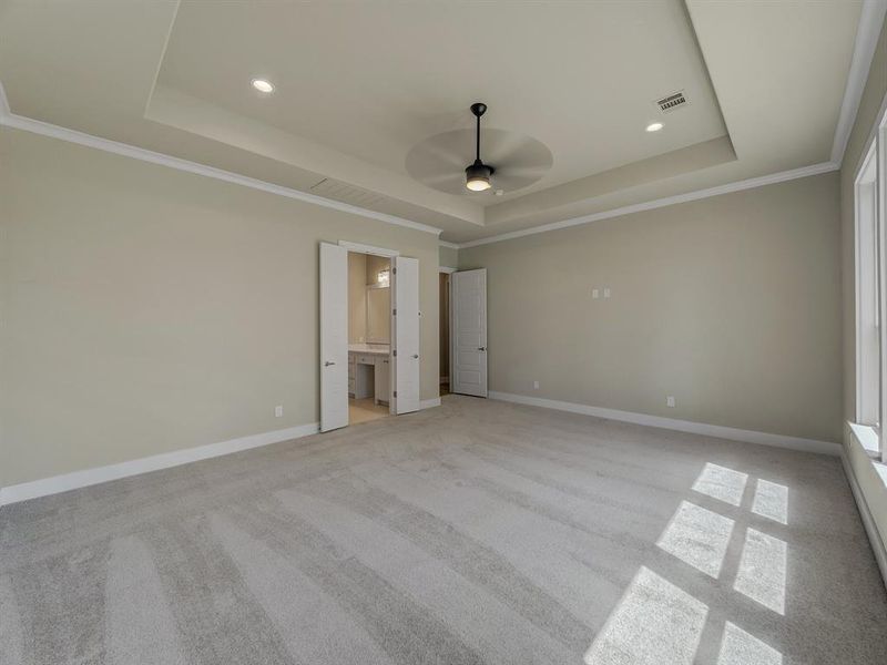 Unfurnished bedroom featuring ornamental molding, light carpet, a tray ceiling, recessed lighting, and connected bathroom Unfurnished bedroom featuring ornamental molding, light carpet, a tray ceiling, recessed lighting, and connected bathroom