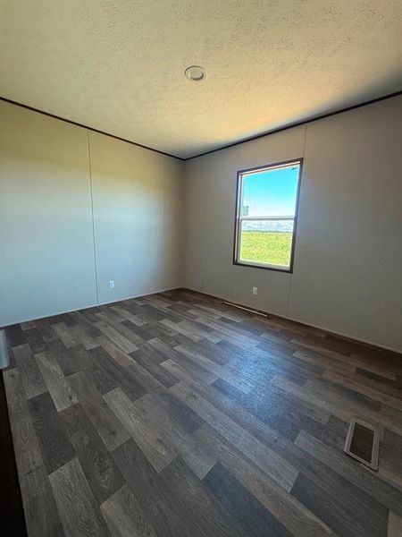 Room featuring wood-finish flooring, neutral wall paneling, and a recessed ceiling light Room featuring wood-finish flooring, neutral wall paneling, and a recessed ceiling light