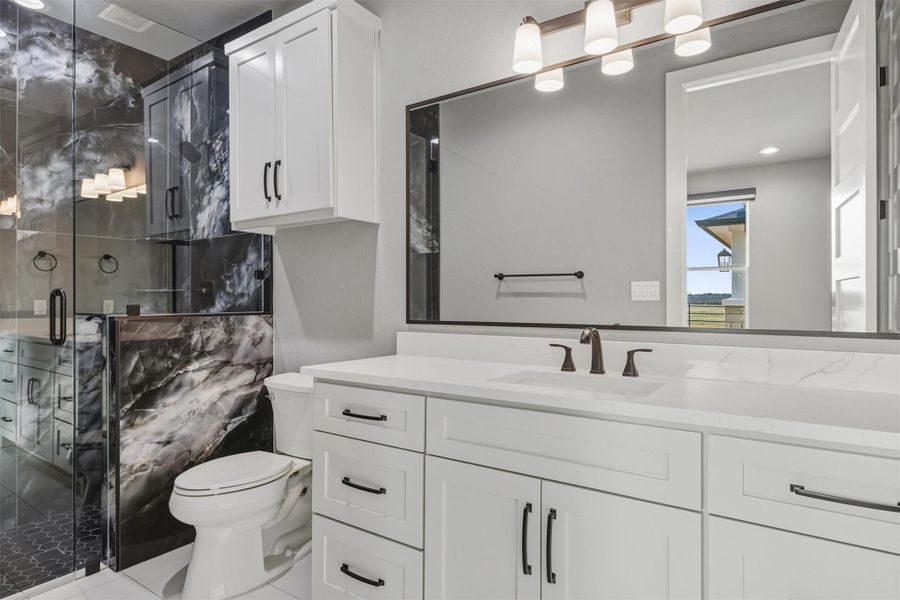 Bathroom featuring a marble finish shower, vanity, and tile patterned floors