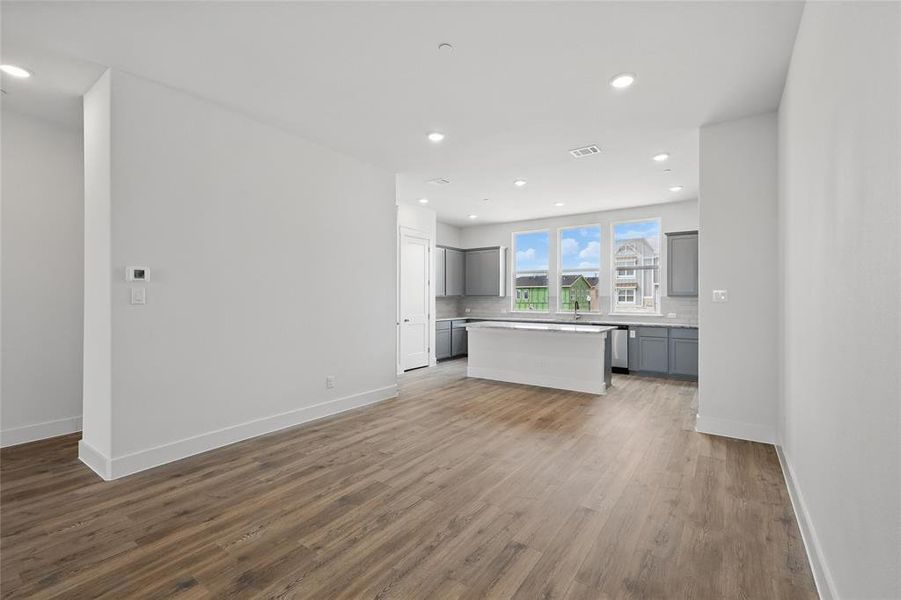 Kitchen featuring a kitchen island, open floor plan, light countertops, dark wood finished floors, and gray cabinets