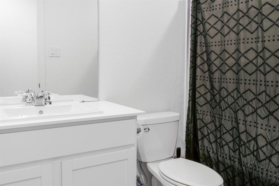 This bathroom features a clean, modern design with a white vanity and sink, & chrome fixtures