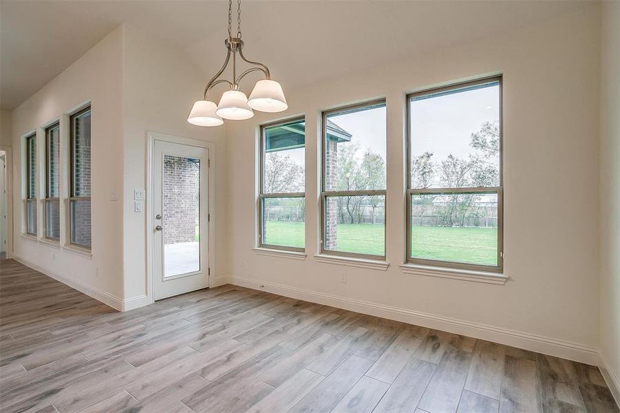 Unfurnished dining area featuring an inviting chandelier and light hardwood / wood-style flooring