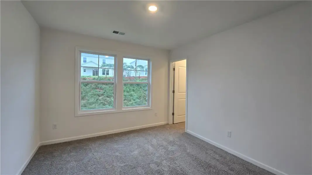 Plush carpeting and dual windows frame views of th