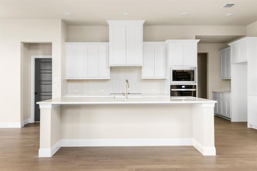 Kitchen featuring oven, light hardwood / wood-style flooring, and an island with sink