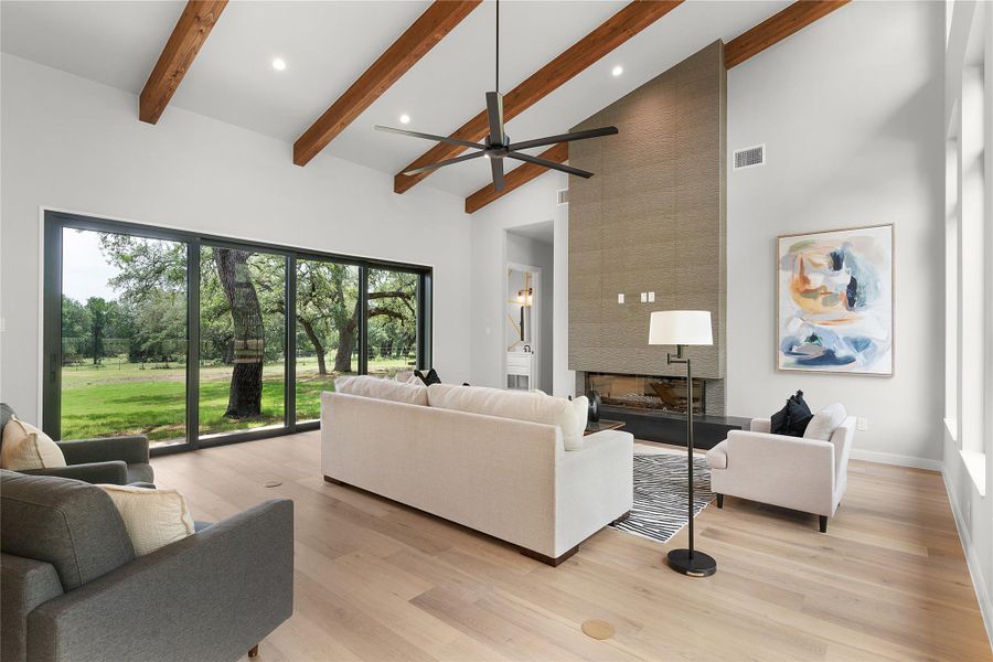 Living area featuring high vaulted ceiling, plenty of natural light, beamed ceiling, ceiling fan, and light wood-type flooring Living area featuring high vaulted ceiling, plenty of natural light, beamed ceiling, ceiling fan, and light wood-type flooring