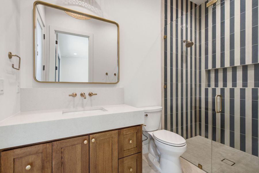 A stylish vanity paired with a glass-enclosed shower featuring bold vertical tile.