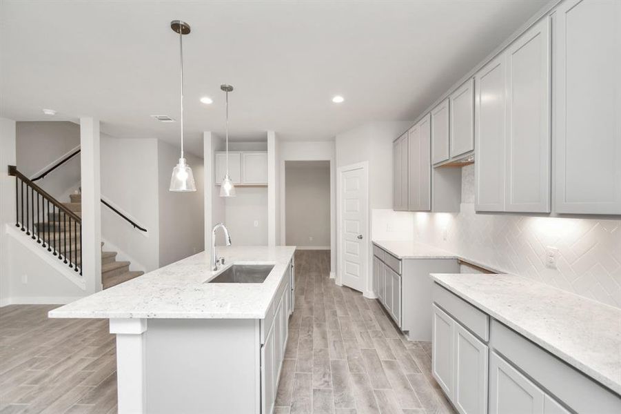 The kitchen is a culinary haven, featuring granite countertops, a tile backsplash, stainless steel appliances, 42” upper cabinets, and undercabinet lighting. Sample photo of completed home with similar floor plan. As-built interior colors and selections may vary.