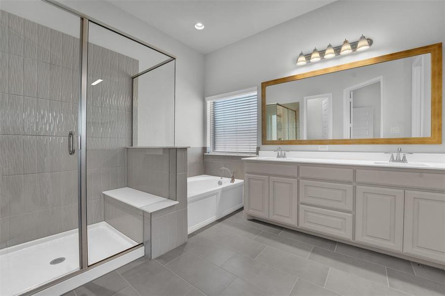 Bathroom featuring double vanity, a garden tub, a shower stall, and light tile patterned floors