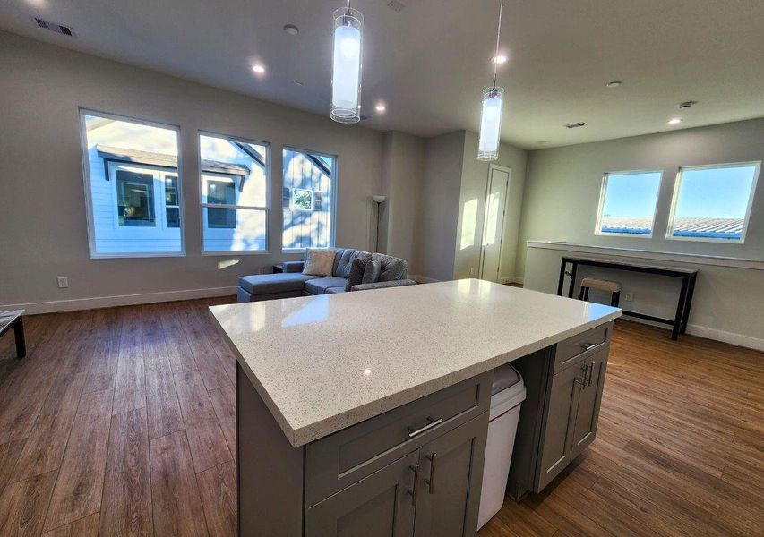 Bright and spacious open-plan living area with wood flooring and modern lighting. Features a large kitchen island, ample windows for natural light, and a cozy seating area. Ideal for entertaining. Bright and spacious open-plan living area with wood flooring and modern lighting. Features a large kitchen island, ample windows for natural light, and a cozy seating area. Ideal for entertaining.