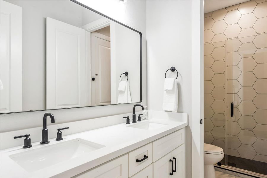 Luxurious second bathroom featuring a sleek double vanity, modern fixtures, and a stylish hexagonal-tiled shower.