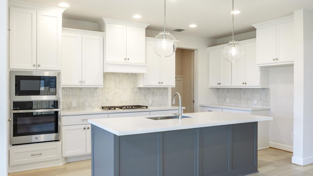Kitchen with stainless steel appliances, white cabinetry, backsplash, and recessed lighting