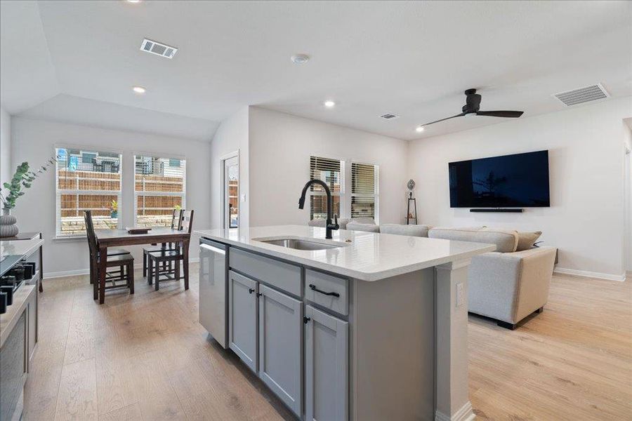 Kitchen featuring visible vents, a sink, light wood-type flooring, gray cabinets, and stainless steel dishwasher