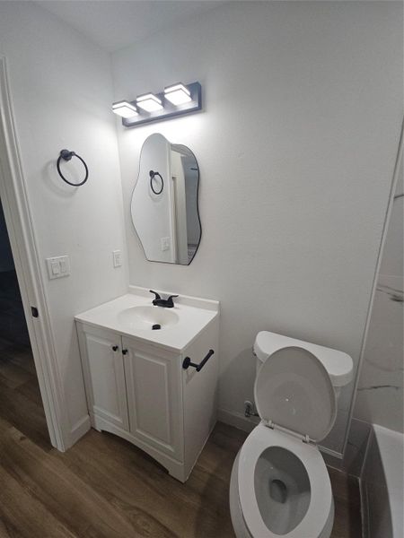 Bathroom featuring toilet, vanity, baseboards, and wood finished floors