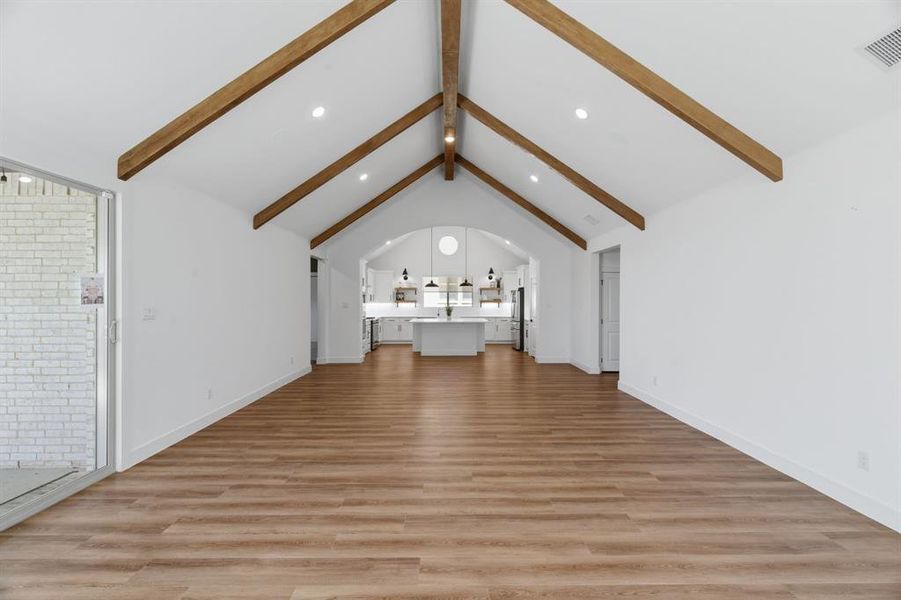 Vaulted ceiling with exposed wood beams, recessed lighting, wood-finish flooring, and a sliding glass door Vaulted ceiling with exposed wood beams, recessed lighting, wood-finish flooring, and a sliding glass door