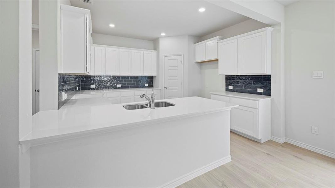 Kitchen featuring a peninsula, white cabinets, light stone counters, tasteful backsplash, and recessed lighting Kitchen featuring a peninsula, white cabinets, light stone counters, tasteful backsplash, and recessed lighting