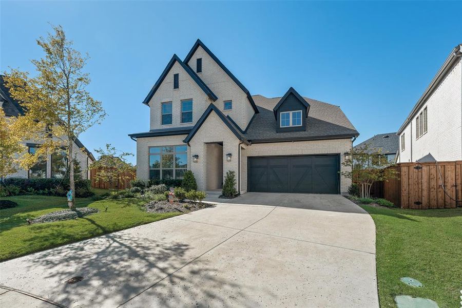 View of front facade featuring brick siding, a garage, concrete driveway, and a shingled roof
