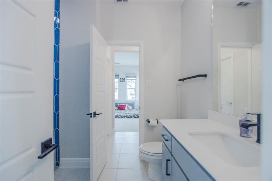 Ensuite bathroom with vanity, visible vents, ensuite bathroom, tile patterned floors, and toilet