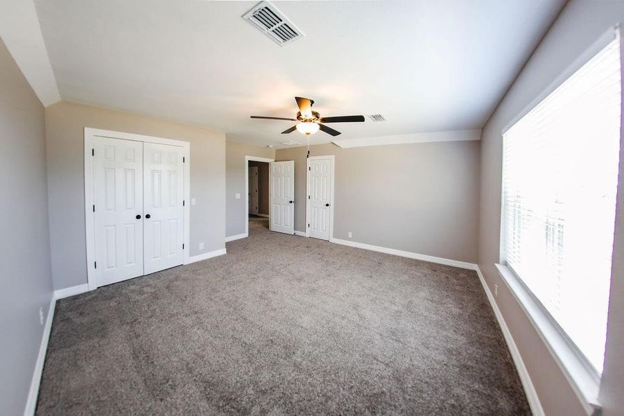 Unfurnished bedroom featuring carpet flooring, a ceiling fan, and multiple closets Unfurnished bedroom featuring carpet flooring, a ceiling fan, and multiple closets