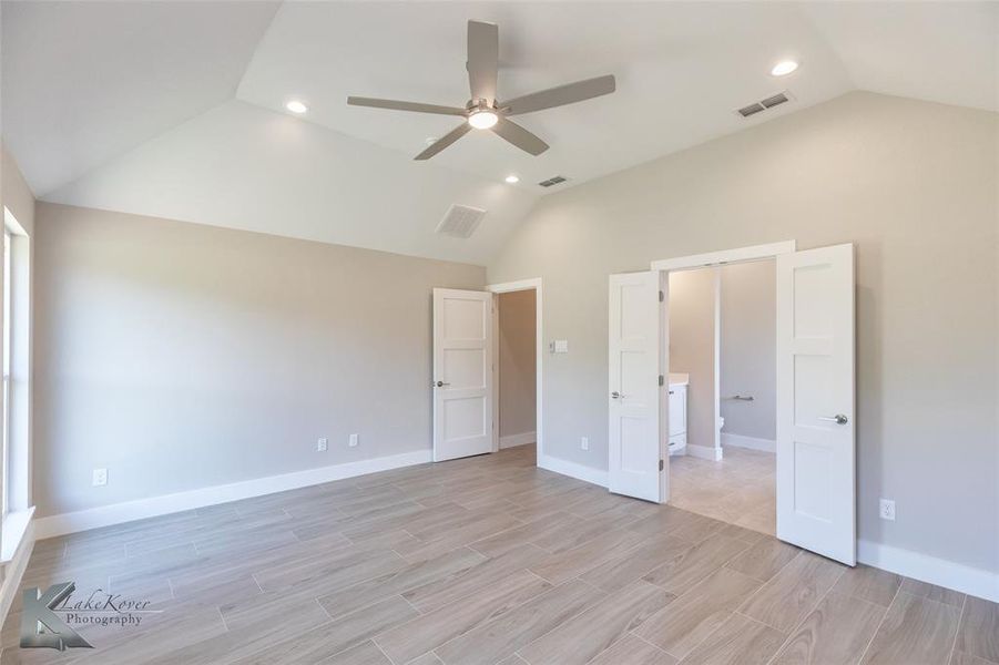 Unfurnished bedroom with lofted ceiling, light wood-style flooring, ceiling fan, and recessed lighting