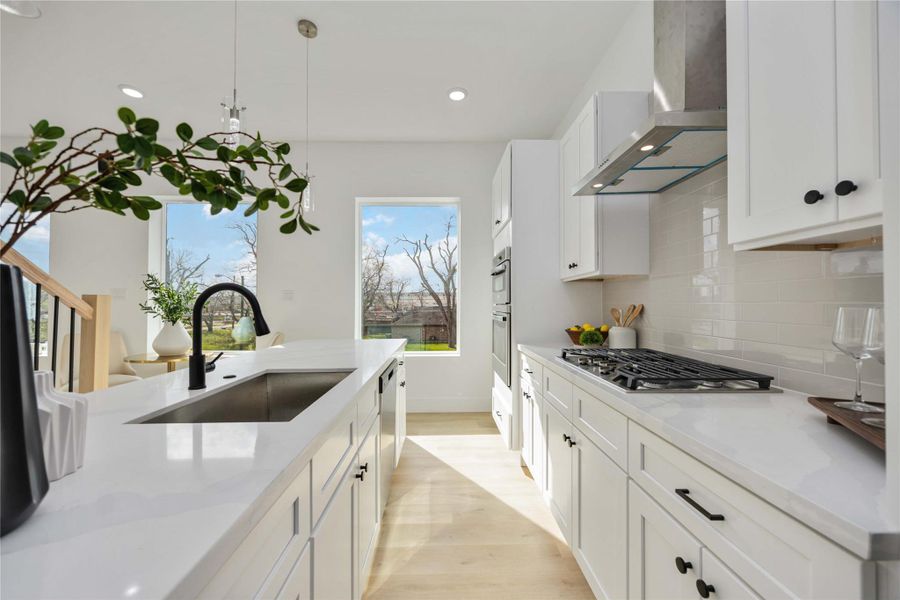 A bright, modern kitchen showcases sleek white cabinetry, polished white quartz countertops, a stylish glossy subway-tile backsplash, and a spacious kitchen island with a matte black sink faucet that adds both function and contemporary flair.