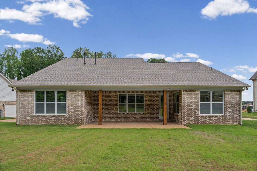 Rear exterior featuring a covered patio with wooden support columns, brick facade, shingle roof, and multiple windows overlooking a grassy yard Rear exterior featuring a covered patio with wooden support columns, brick facade, shingle roof, and multiple windows overlooking a grassy yard