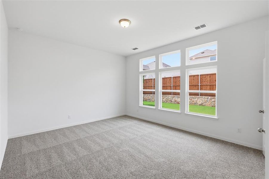 Bright room featuring a large bank of six windows, light-colored walls, and gray patterned carpet